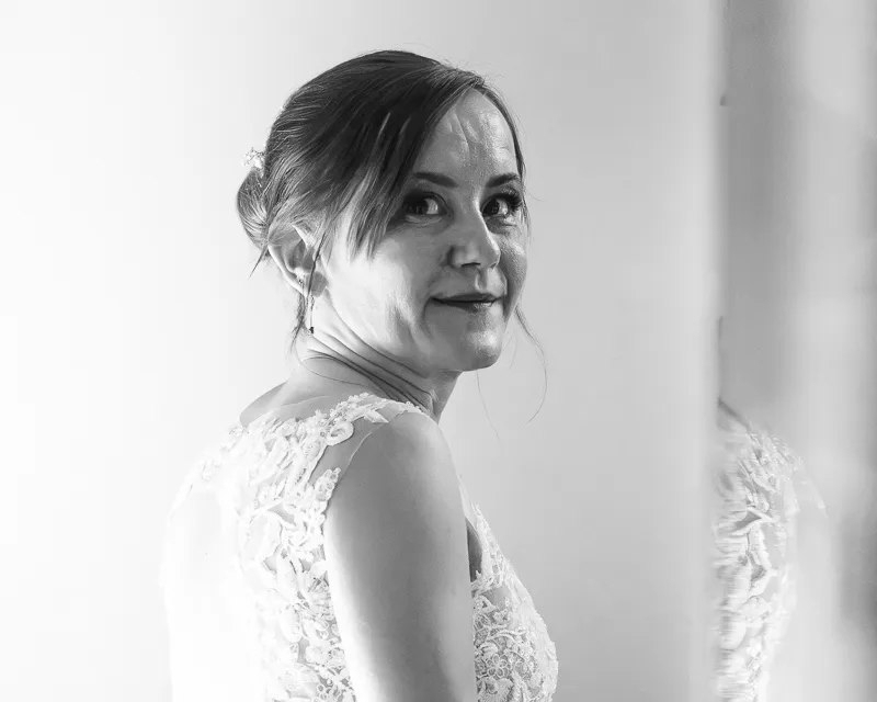 Braut im Hochzeitskleid blickt während der Vorbereitung in die Kamera
